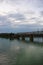 The gray Samara railway bridge over the surface of the Samara river with a beautiful landscape, green trees, bushes and greenery.