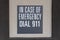 Gray sign on the wall depicting the emergency number, sign with inscription: in case of emergency