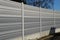 gray and silver protective fencing separates housing from a busy noisy road. the porous material shatters tire noise well