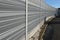 gray and silver protective fencing separates housing from a busy noisy road. the porous material shatters tire noise well