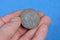 Gray soviet ruble coin in fingers on blue background