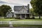a gray stone farmhouse with a manicured lawn and a picket fence