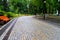 Gray stone walkway in the morning autumn park with orange benches. Mariinsky Park near the Parliament of Ukraine, Verkhovna Rada,