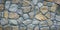 Gray stone wall. Texture of grey granite. Uneven rock surface of floor, decorative tile of facade building. Wide panorama. Mosaic