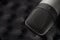 Gray studio condenser microphone on black soft foam