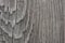 The gray surface of an old wooden board. Rough weathered texture. Vertical drawing of annual rings of wood. Dark background or