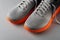 Gray textile sneakers with orange sole over grey background