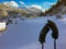 Gray thick winter gloves on hiking trekking sticks on fresh snow