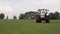 Gray tractor rides on the green field