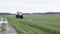 Gray tractor rides on the green field