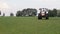 Gray tractor rides on the green field