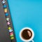 Gray weekly planner with bookmarks and a cup of coffee on a blue background. Business planning and personal growth concept