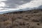 Gray and white clouds winter landscape desert valley fence with snowy mountain range