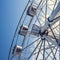 Gray or white metal ferris wheel with closed passenger cabins close-up in the amusement park