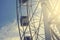 Gray or white metal ferris wheel with closed passenger cabins close-up in the amusement park