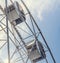 Gray or white metal ferris wheel with closed passenger cabins close-up in the amusement park