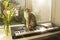 A gray-white tabby cat sits on a synthesizer against the background of a window.