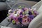 a gray wicker basket with pink white and purple flowers sits on the front seat of a luxury