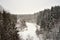 Gray winterday with light snowfall and scenery to frozen river