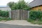 Gray wooden gate and a fence overgrown with fences near the asphalt road