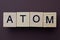 Gray word atom from small wooden letters