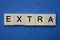 Gray word extra in small square wooden letters