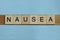Gray word nausea in small square wooden letters