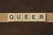 Gray word queer made of wooden square letters