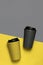 Gray and yellow eco cups on ultimate gray and illuminating background. Concept of zero waste living and color of the year 2021