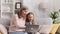 Grayhaired grandmother and little granddaughter are sitting on the sofa in the living room, resting and watching funny