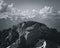 Grayscale aerial view of rocky mountains under a cloudy sky