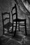 Grayscale low-angle shot of a wooden chair with a shadow on the wall