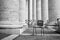 Grayscale shot of an abandoned plastic chair in a building with columns in Rome