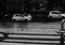 Grayscale shot of cars driving through the road during the rain