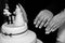 Grayscale shot of  hands of a  wedding couple over a wedding cake with male and female figures on it