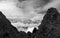 Grayscale shot of jagged rocky mountain peaks surrounded by clouds