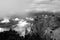 Grayscale shot of jagged rocky mountain peaks surrounded by clouds