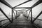 Grayscale shot of light at the end of a modern beautifully architectured bridge surrounded by fog