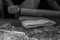Grayscale shot of a man preparing the dough for puff pastry with a wooden rolling pin