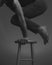 Grayscale shot of a person raising his body with his arms on a stool