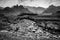 Grayscale shot of a river with tall mountains in the background