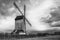 Grayscale shot of a rural windmill in a field on a cloudy day
