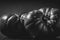 Grayscale shot of two ripe Spanish tomatoes on a solid tabletop, isolated on a blank background