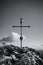 Grayscale vertical shot of a Christian metal cross standing on the rock