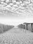 Grayscale vertical shot of striped beach tents under stratus clouded sky