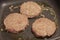 Greasy hamburger patty frying in a pan