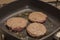 Greasy hamburger patty frying in a pan