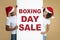 Great big seasonal boxing day sale. Interested african american man and woman in christmas hats hold banner