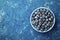 Great bilberry or blueberry in bowl on blue rustic background top view. Vintage style. Flat lay.