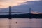 Great blue heron perched on a rock in the St. Lawrence River and the Island of Orleans Bridge seen in silhouette at dawn